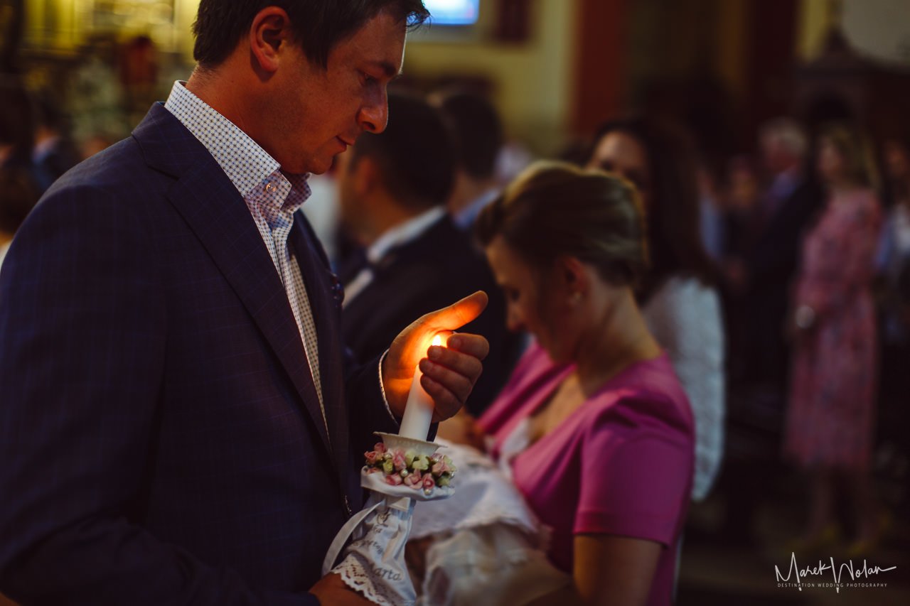 ojciec chrzestny trzymający świece